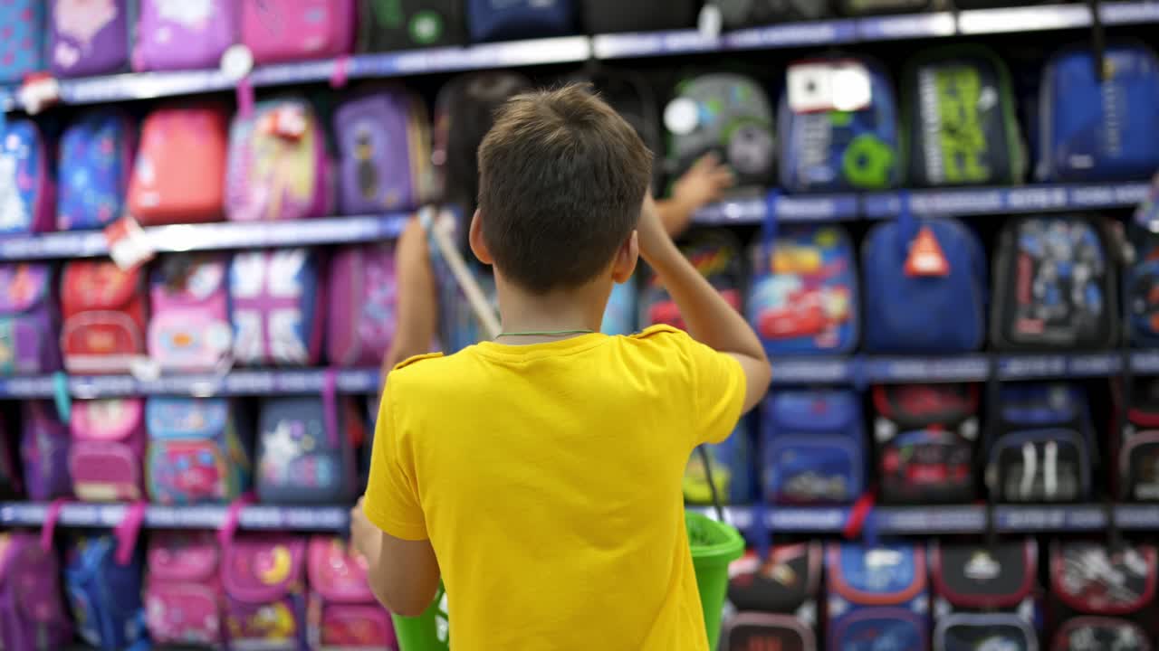Boy choosing backpack. Rear view of boy selecting school bag in supermarket
