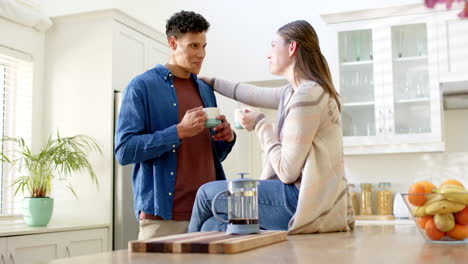 pareja feliz hablando y bebiendo café en la cocina en casa, en cámara lenta