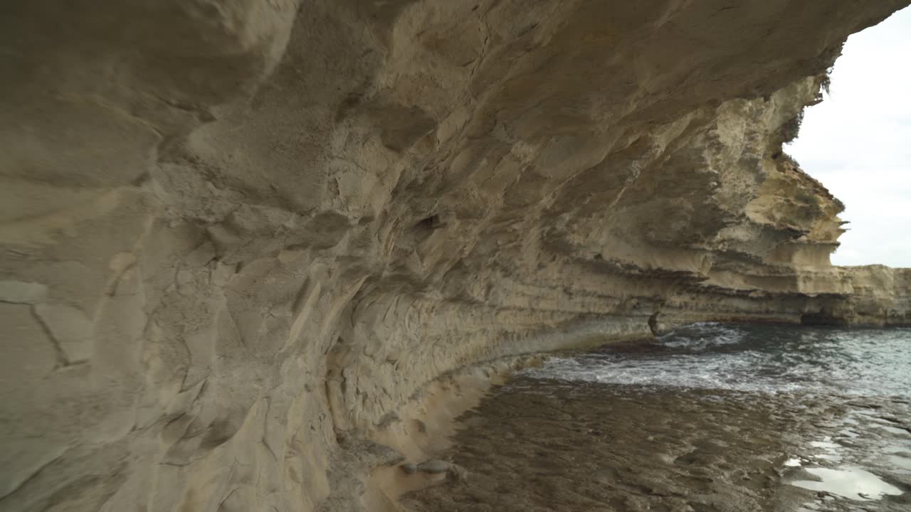 pared de piedra caliza cerca de la playa de il-kalanka en malta con agua salpicada en la bahía