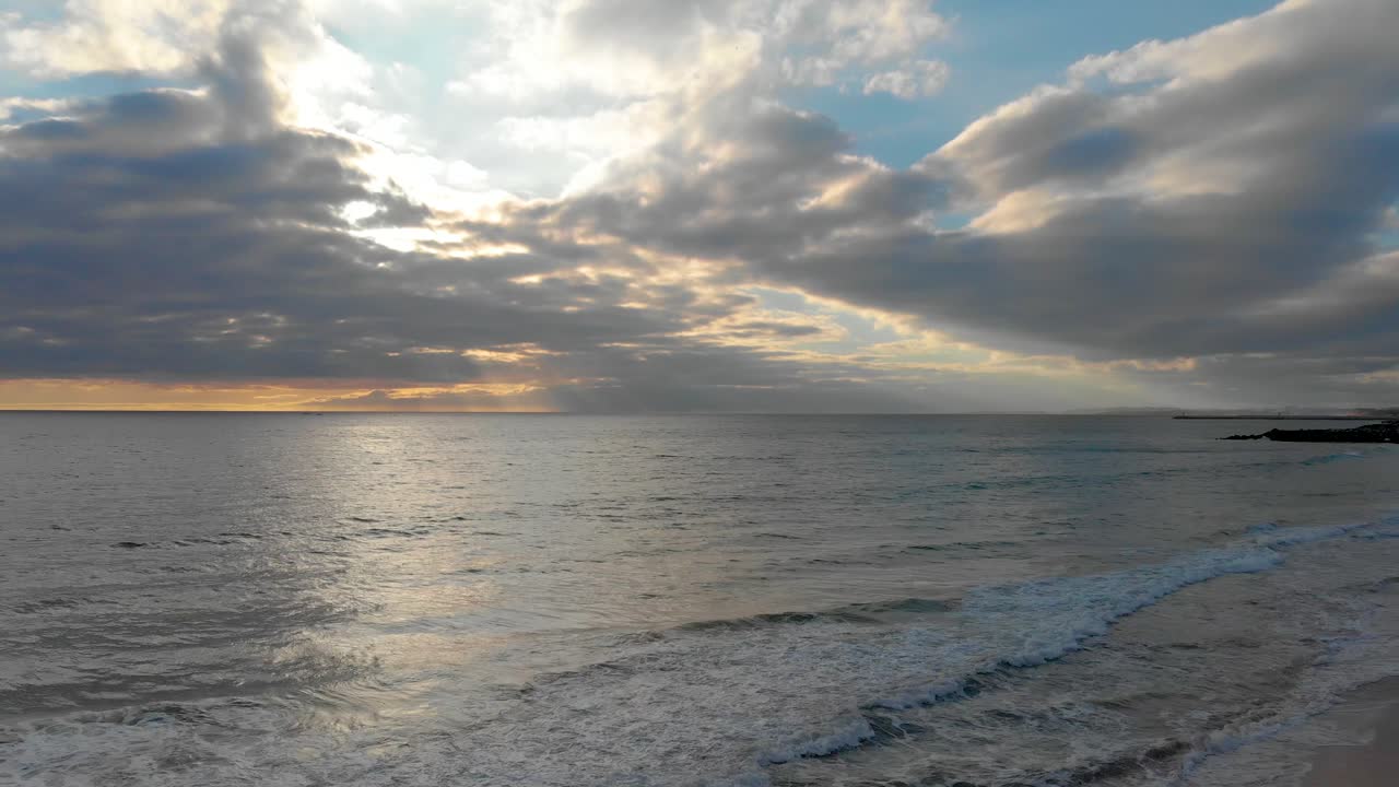 Tramonto con un cielo nuvoloso e una costa oceanica calma