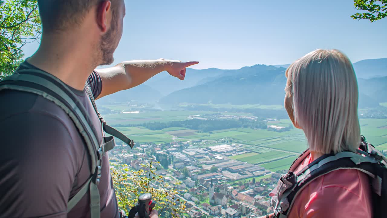 Wide angle dolly in shot of a man and women standing and watching the spectacular Green window, panoramic view point in Radlje on Dravi during the day