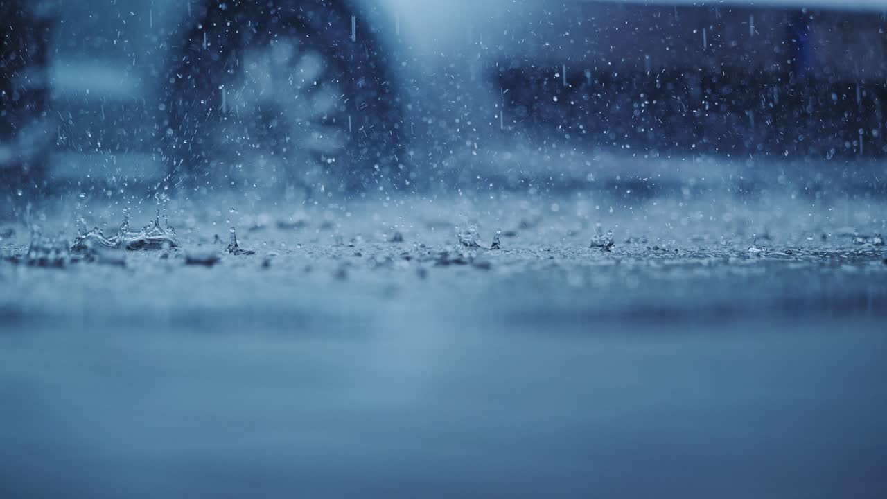 Slow motion storm shows heavy urban rain overwhelming pavement with splashes