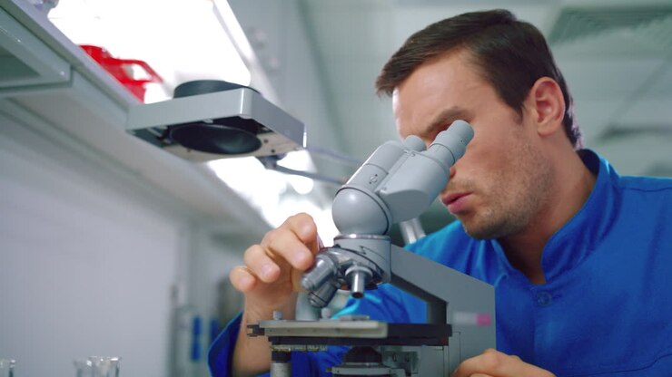 Scientist student working with microscope. Male scientist looking microscope