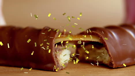 animation of gold confetti falling over broken biscuit and caramel chocolate bar