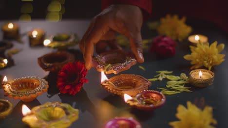 fotografía de cerca de un hombre encendiendo lámparas de aceite diya celebrando el festival de diwali