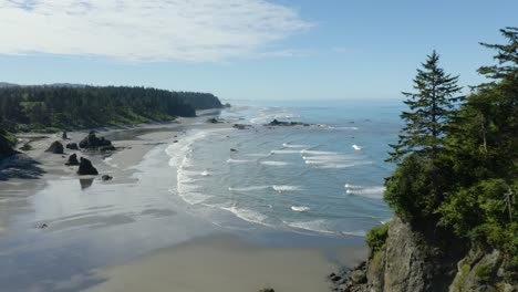 drone flies backwards revealing massive boulder on coastal ruby beach in olympic national park, washington state