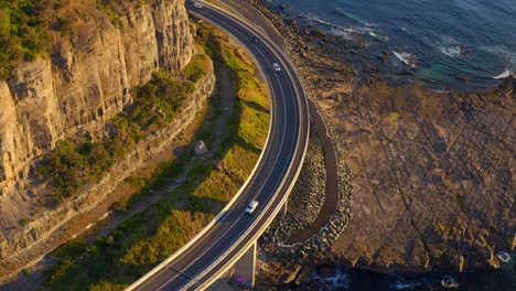 aerial view of the iconic sea cliff bridge with cars traveling on the structure along the beautiful coast in the northern illawarra region of new south wales, australia - drone shot