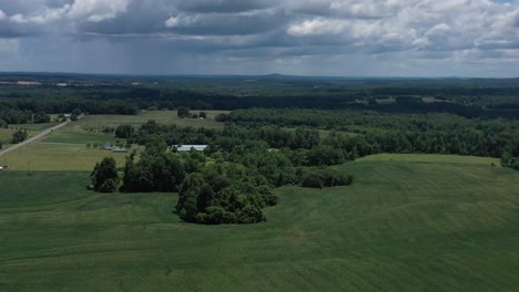 drone descent revealing a cornfield and rural land with rain and rain clouds in the background