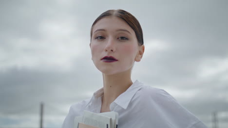 portrait relaxed business lady holding documents folder in front cloudy sky.