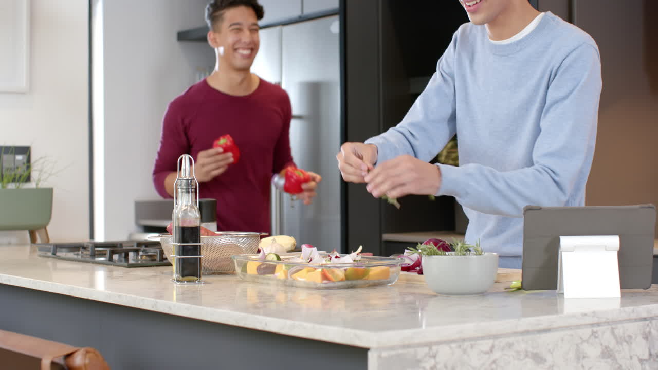 Preparing meal, multiracial gay couple enjoying time in modern kitchen, at home