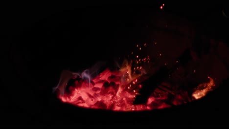 glowing hot wood coals being preped by a male hand in slow motion