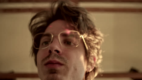 close-up of a man with glasses and mustache looking up