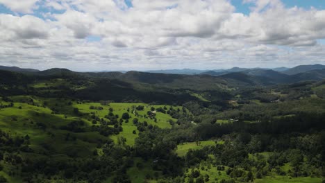 Nubes-Que-Proyectan-Sombras-Sobre-Un-Exuberante-Valle-Verde-Que-Conduce-A-Una-Cordillera-Lejana