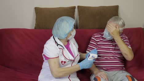 la enfermera mide la temperatura con un termómetro electrónico sin contacto del abuelo enfermo. coronavirus