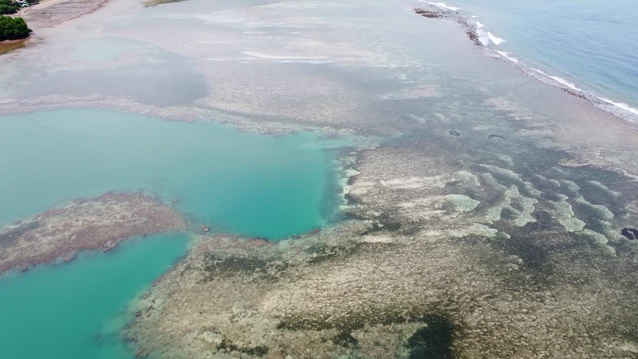 Aerial view flyover ocean with turquoise water and patterned rock and sand formation in Timor-Leste, Southeast Asia