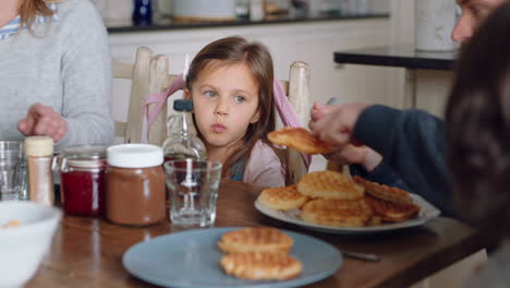 happy family eating breakfast waffles with children enjoying delicious treat in kitchen at home