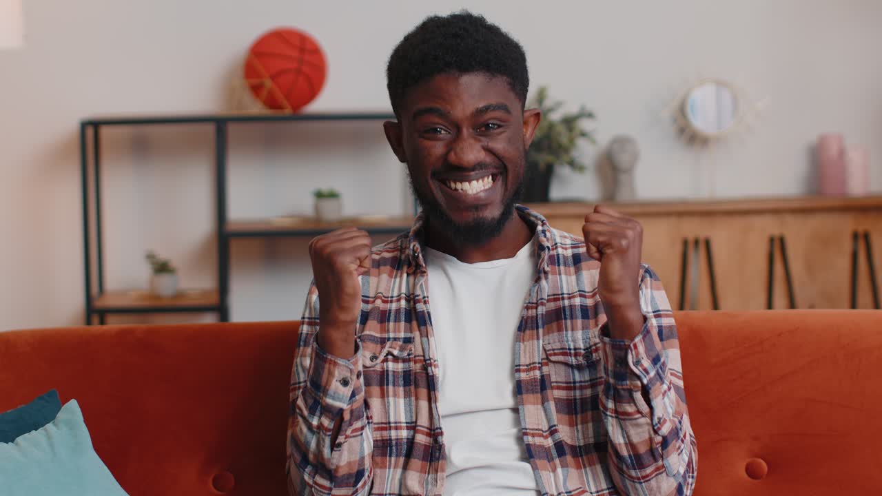 Young adult man shouting raising fists in gesture i did it celebrating success winning at home