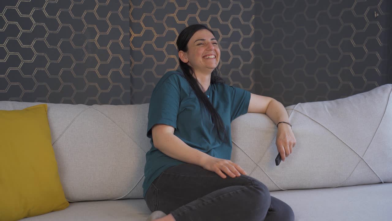 tv에서 코미디를 보는 여자가 웃습니다.