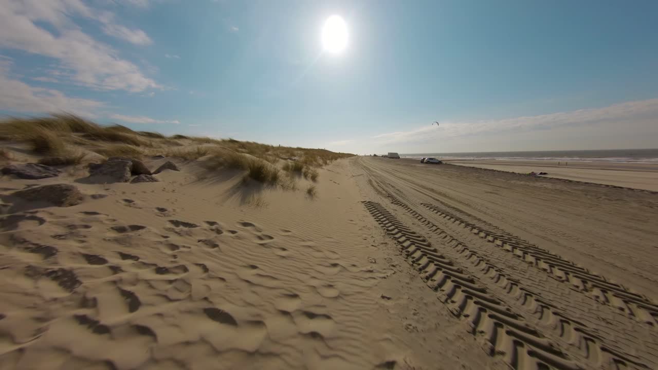 Aerial drone flight over golden Domburg beach with kite surfers in background