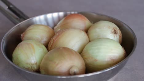 stainless pan with unpeeled white onions