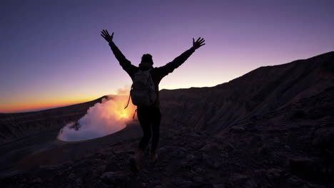 hiker celebrating sunrise at volcano