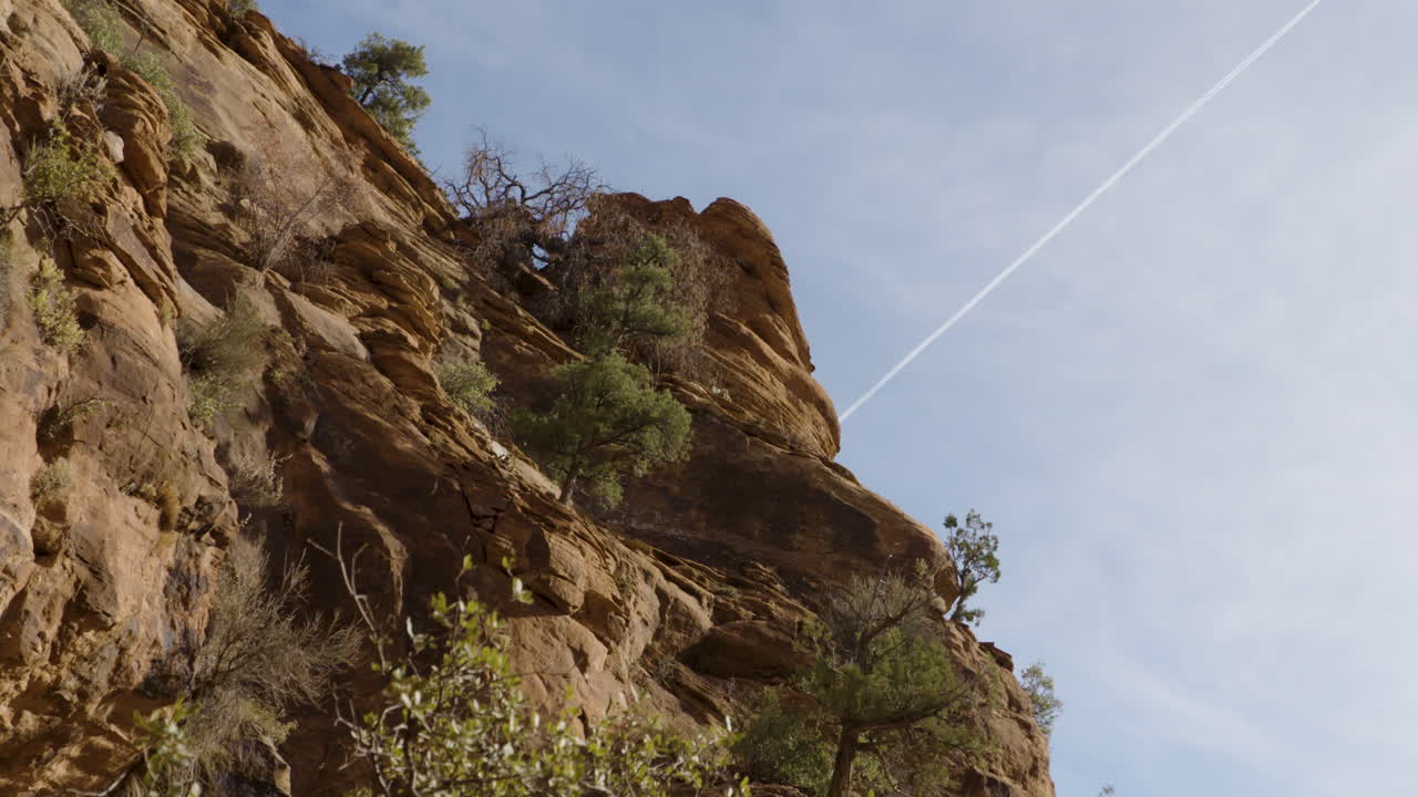 pared de roca de nevada y la estela de un avión en el cielo