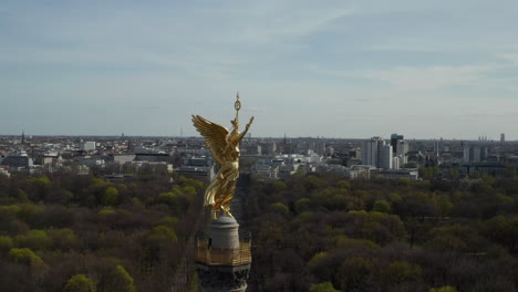 AERIAL:-Close-Up-Circling-around-Berlin-Victory-Column-Golden-Statue-Victoria-in-Beautiful-Sunlight-and-Brandenburg-Gate-in-Background