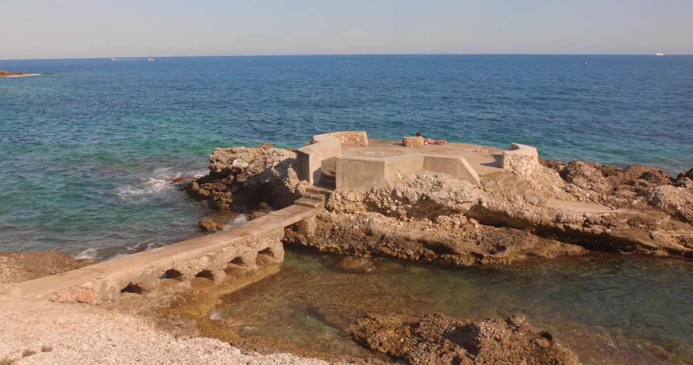 Litorale roccioso a Cap d'Ail con acqua cristallina del Mediterraneo, rocce costiere e strutture storiche sul mare lungo la pittoresca Costa Azzurra vicino a Monaco