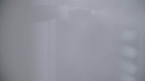 primer plano de una máquina industrial que rocía lentamente vapor transparente sobre una superficie irreconocible en una toma manual de estilo documental