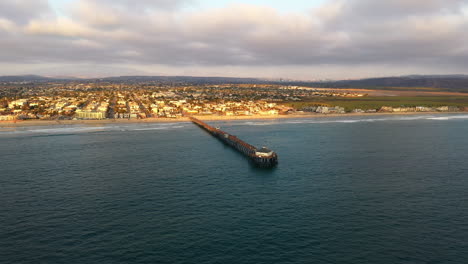 aerial drone wide shot imperial beach pier with tijuana mexico skyline in the distance