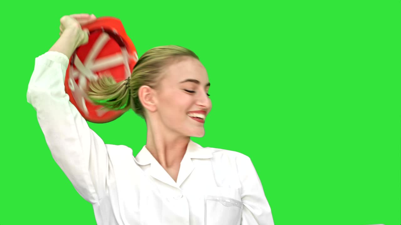 오렌지색 헬을 입은 매우 행복한 여성이 승리하고 녹색 화면에서 그녀의 성공적인 승리를 축하합니다.