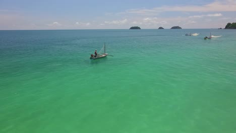 aerial forward dolly shot of a traditional shrimp fisherman on small wooden boats in thailand with small islands in the background