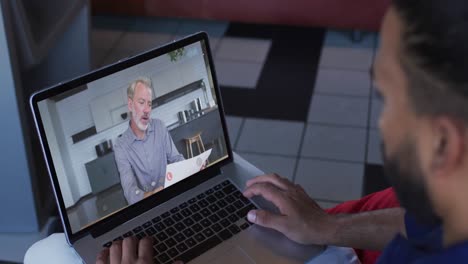 Afroamerikanischer-Mann,-Der-Zu-Hause-Einen-Videoanruf-Mit-Einem-Männlichen-Bürokollegen-Auf-Dem-Laptop-Führt