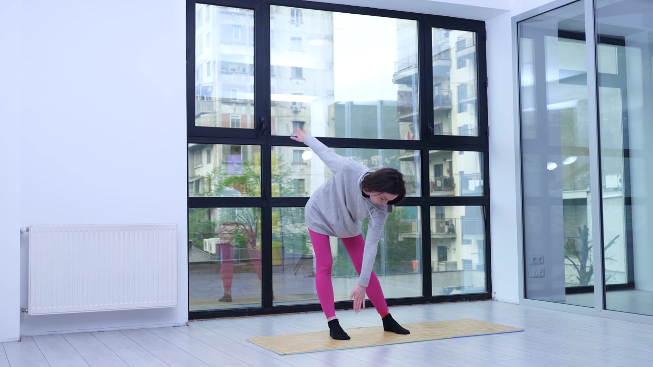 Woman stretches on yoga mat during bright morning workout
