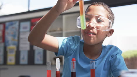 in school, a young african american student examines a test tube in the classroom