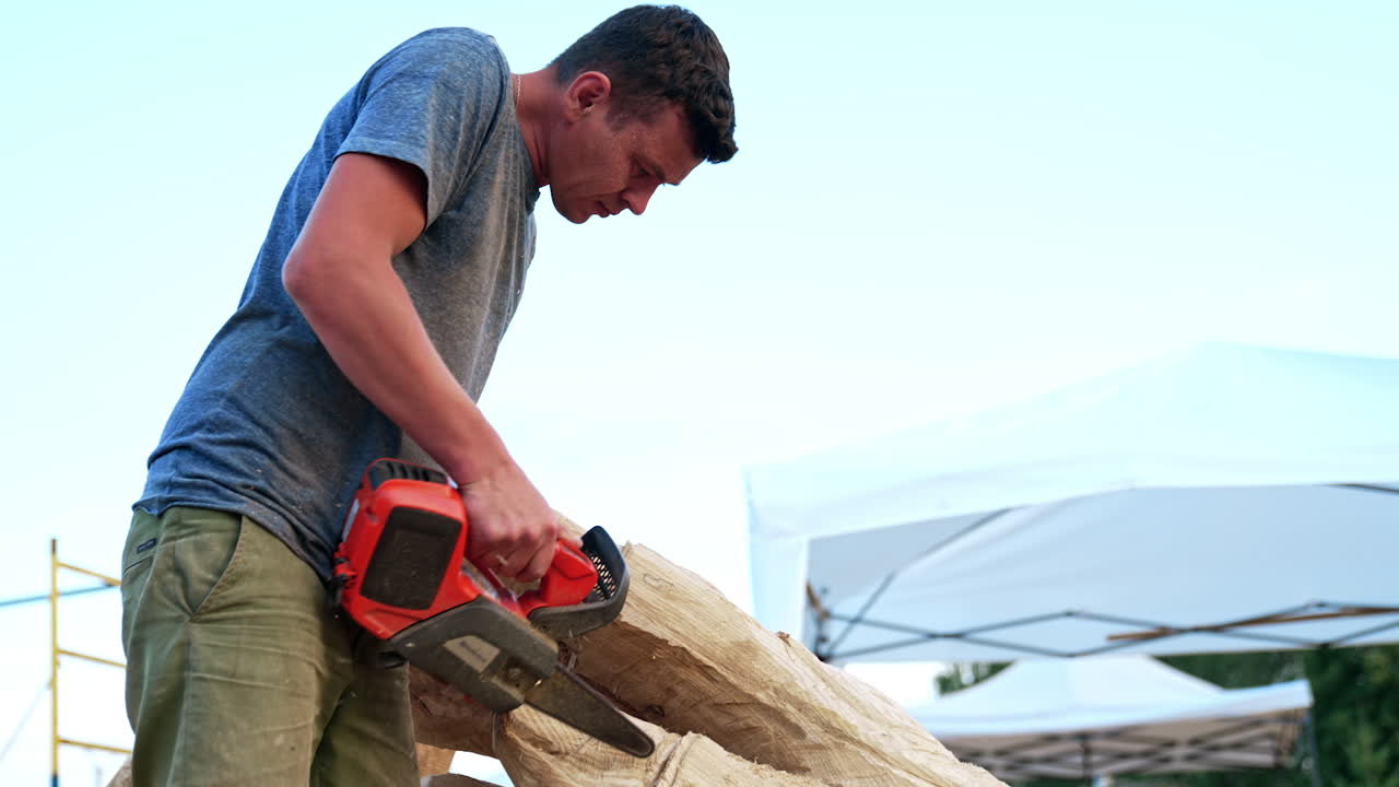Art of sculpture from a timber. Caucasia man cutting wood with chainsaw to create a big hand.