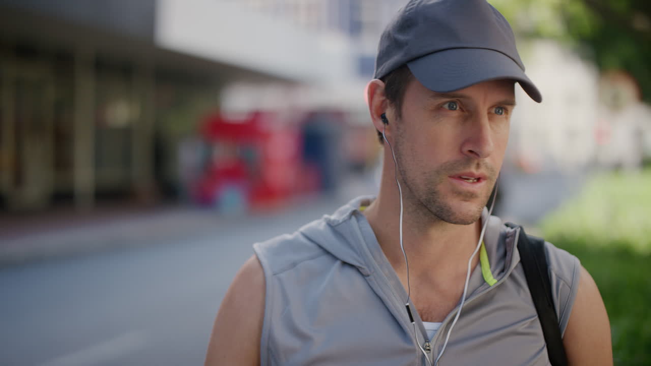 portrait of young fit man puts on earphones sportsman waiting in city street listening to music enjoying healthy urban lifestyle