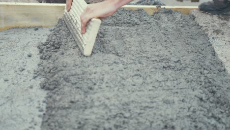 compacting working rough cement with wooden board close up slow motion