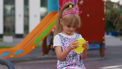 Niña-Niño-Jugando-Apretando-Juguetes-Antiestrés-Pop-It-Juego-Blando-Con-Hoyuelos-Simples-En-El-Patio-De-Recreo