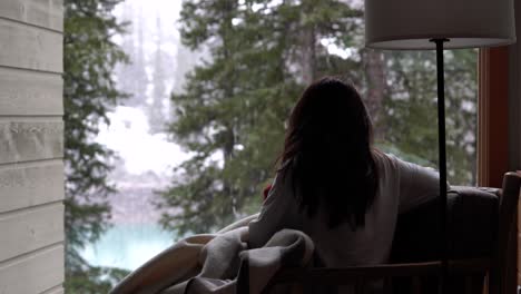 woman enjoying a beautiful snow day in a cozy winter cabin