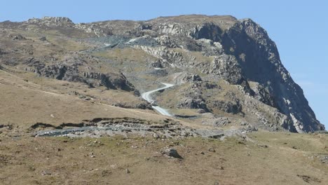 Tractor-coming-down-very-steep-road-in-the-lake-district-mountains-with-a-trailer-full-of-stone