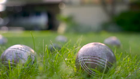 close-up view of a metal petanque ball on the grass, then the player throw another ball nearby