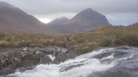 the view of the cuillins and a rushing stream in sligachan on an overcast day