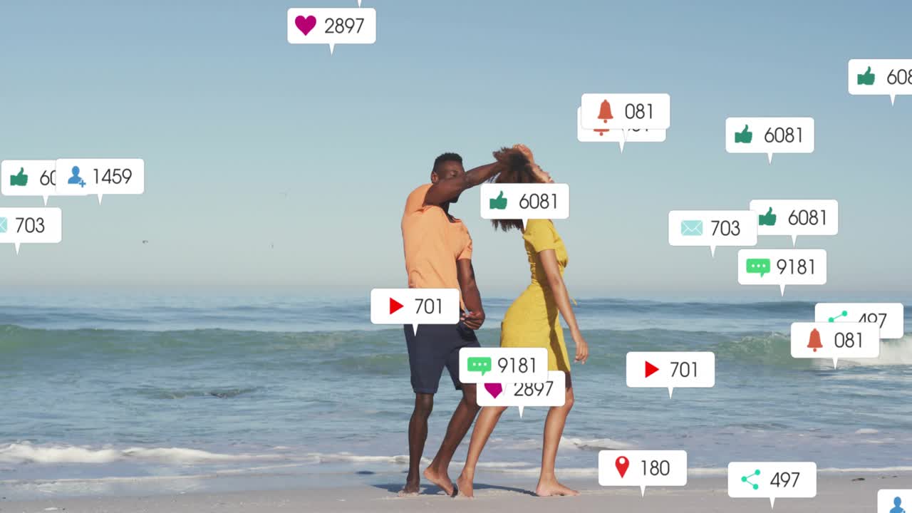 Couple holding hands on shore starting social media icons swirling then fading around duo dancing