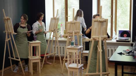 four female students painting at art lesson in art studio