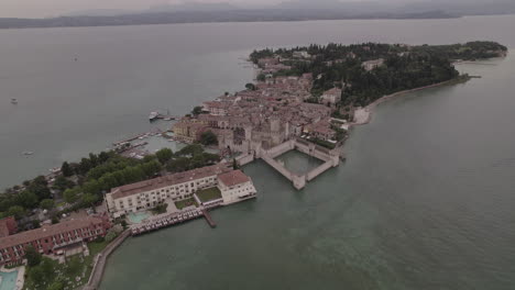 Drone-shot-of-Simione-Italy-looking-over-the-old-fortress-on-a-grey-day-with-boats-around-in-the-water-near-the-lake-LOG