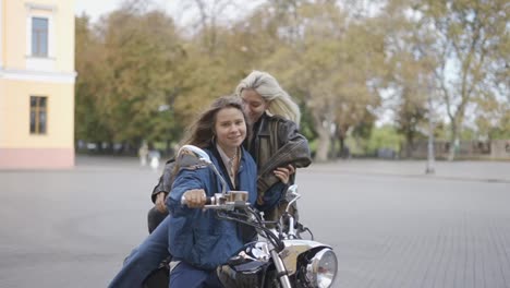 Zwei-Schöne-Junge-Frauen-Sitzen-Auf-Einem-Motorrad-Auf-Der-Stadtstraße-Und-Lächeln