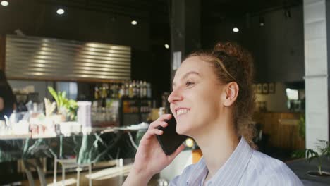 una mujer hablando por teléfono en un café.