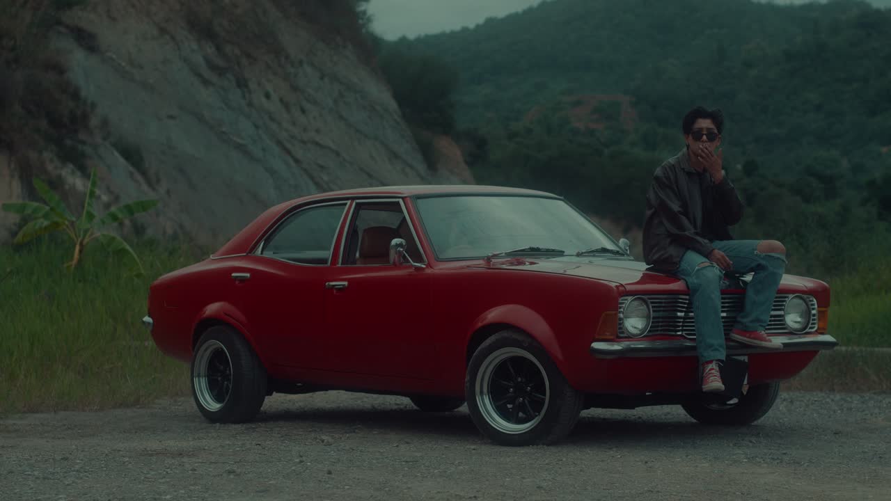 Man sitting on a vintage red car outdoors