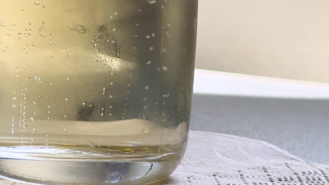 Macro shot of carbonated bubbles rising in a glass of champagne on a tray